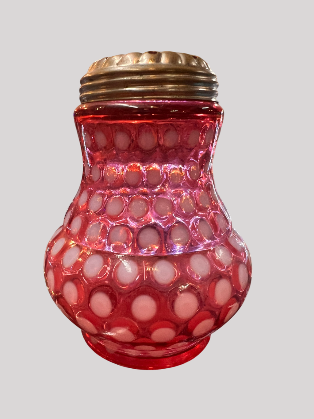 This is a cranberry opalescent coinspot (or inverted thumbprint) glass jar with a metal flower frog lid (used to arrange flowers)