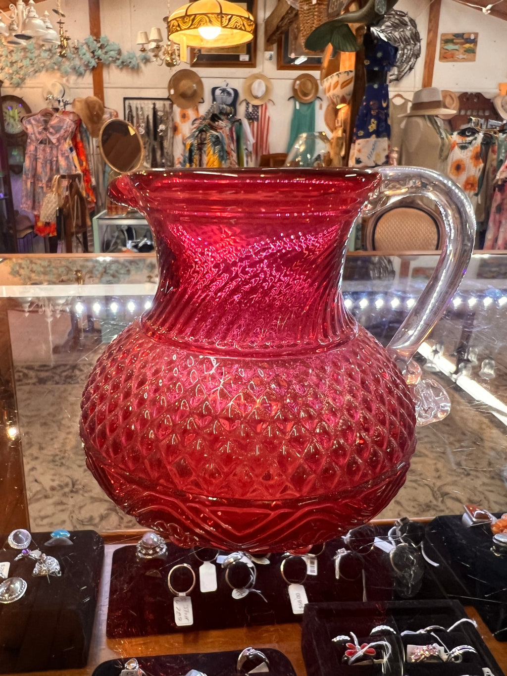 Small hand-blown ruby red art glass pitcher with diamond quilted pattern, clear applied handle, and pontil scar. Likely mid–20th century studio or decorative art glass