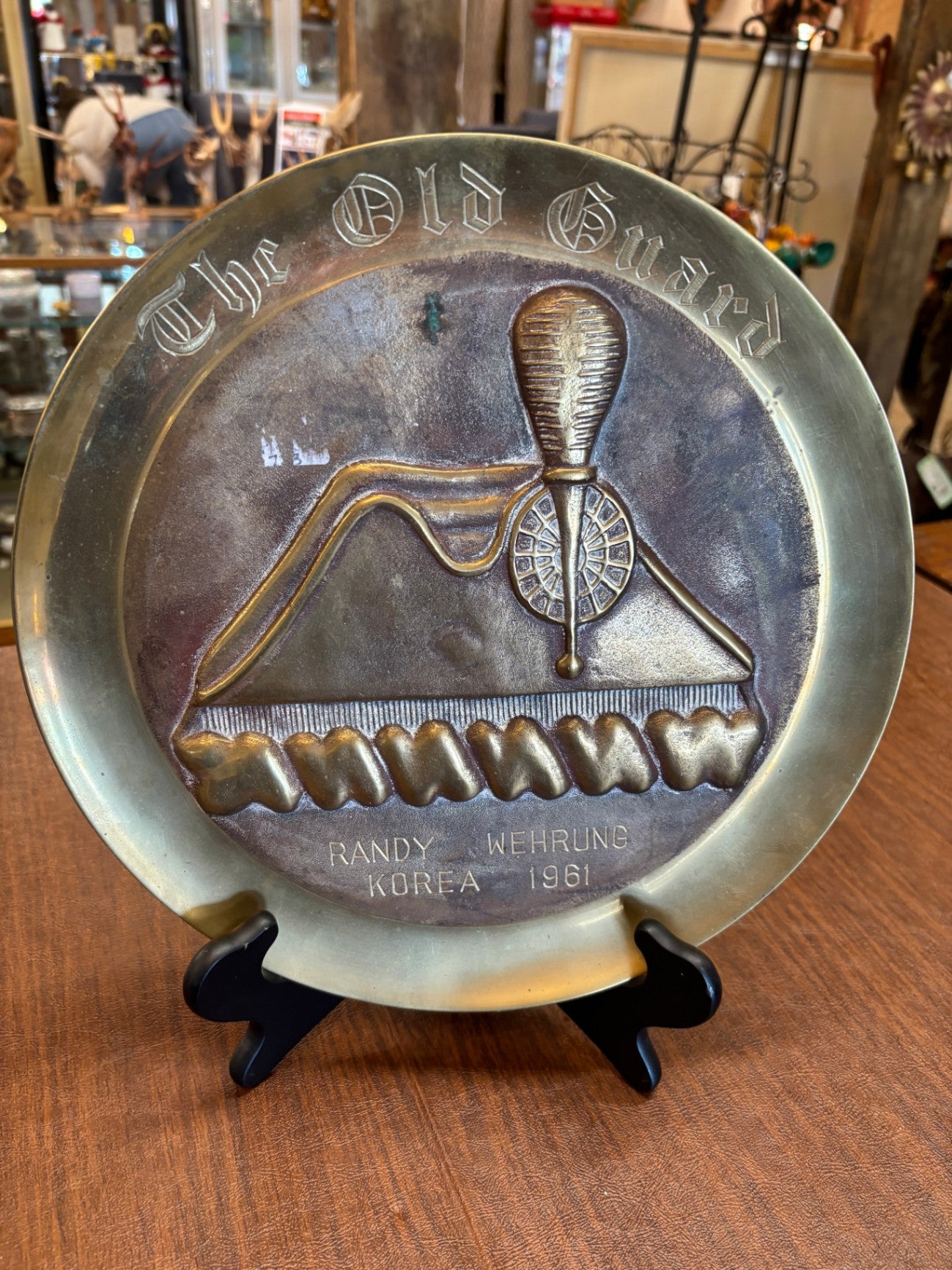  vintage, hand-hammered brass or copper decorative plate featuring a raised design related to a military unit named "The Old Guard"