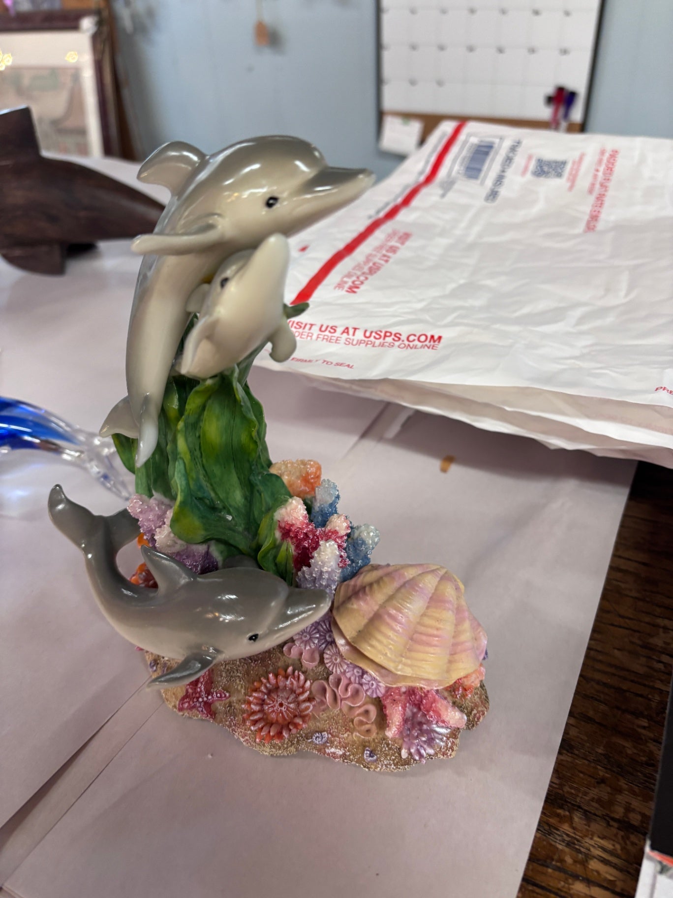 Family of dolphins leaping through a coral reef decorated with seashells and seaweed