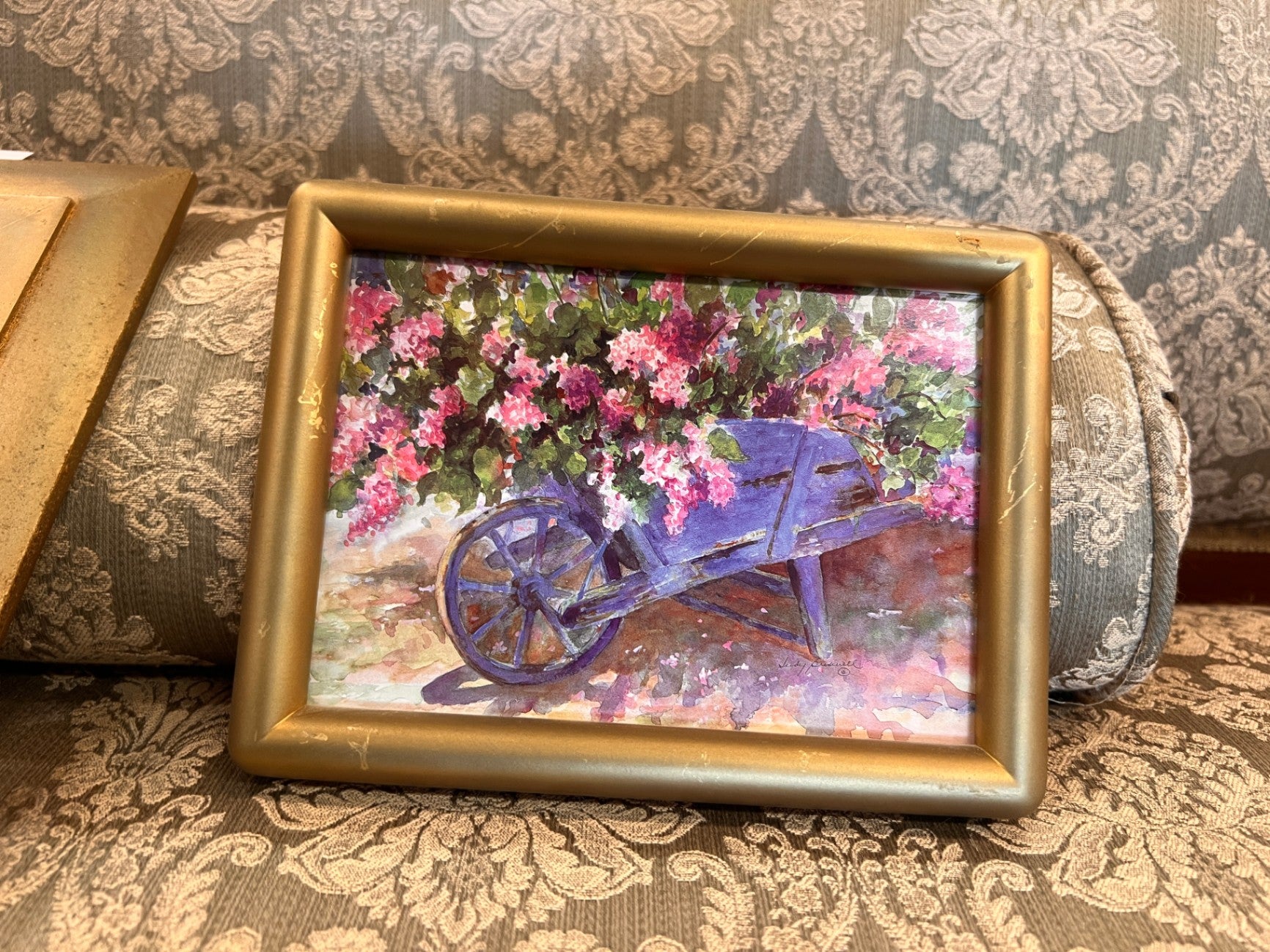 Purple, Pink, Green, Blue Wood (for the wheelbarrow), Watercolor paper or canvas (for the artwork) Decorative Wall Hanging None visible