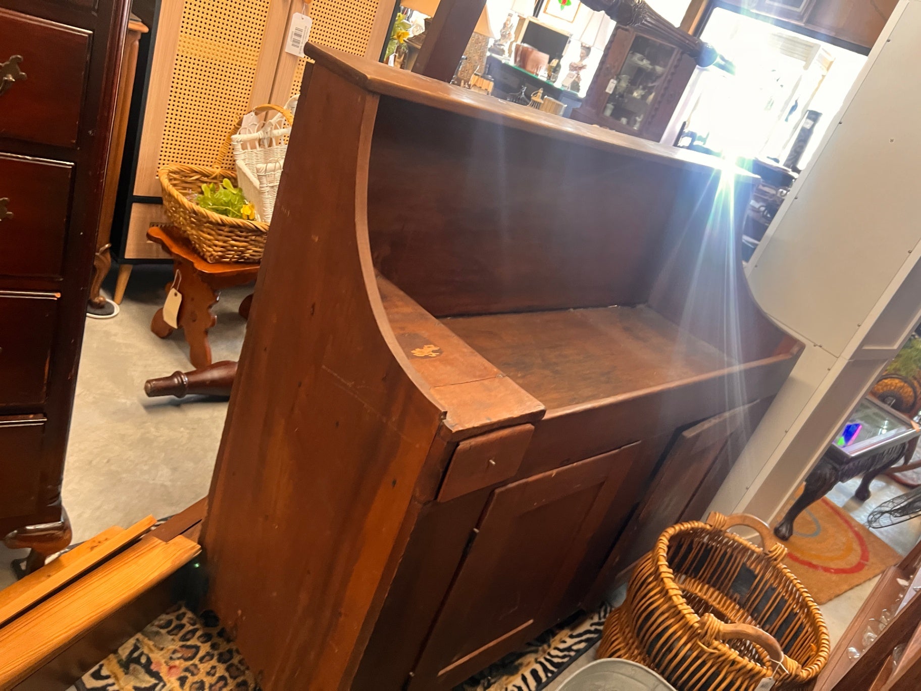 This item is an antique wooden dry sink, a primitive piece of furniture featuring a deep rectangular top area and a paneled door base. 
