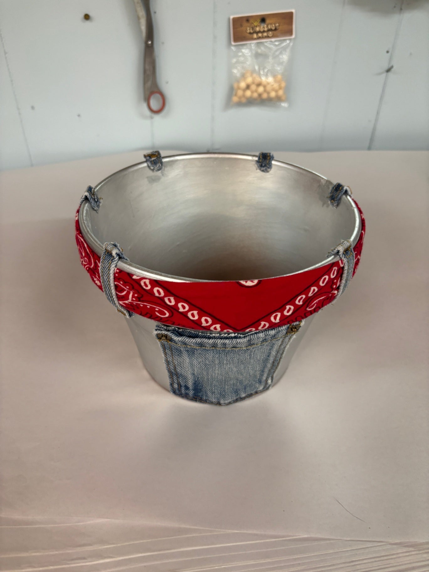 This custom metal craft pail features a red paisley bandana and repurposed denim pocket detail