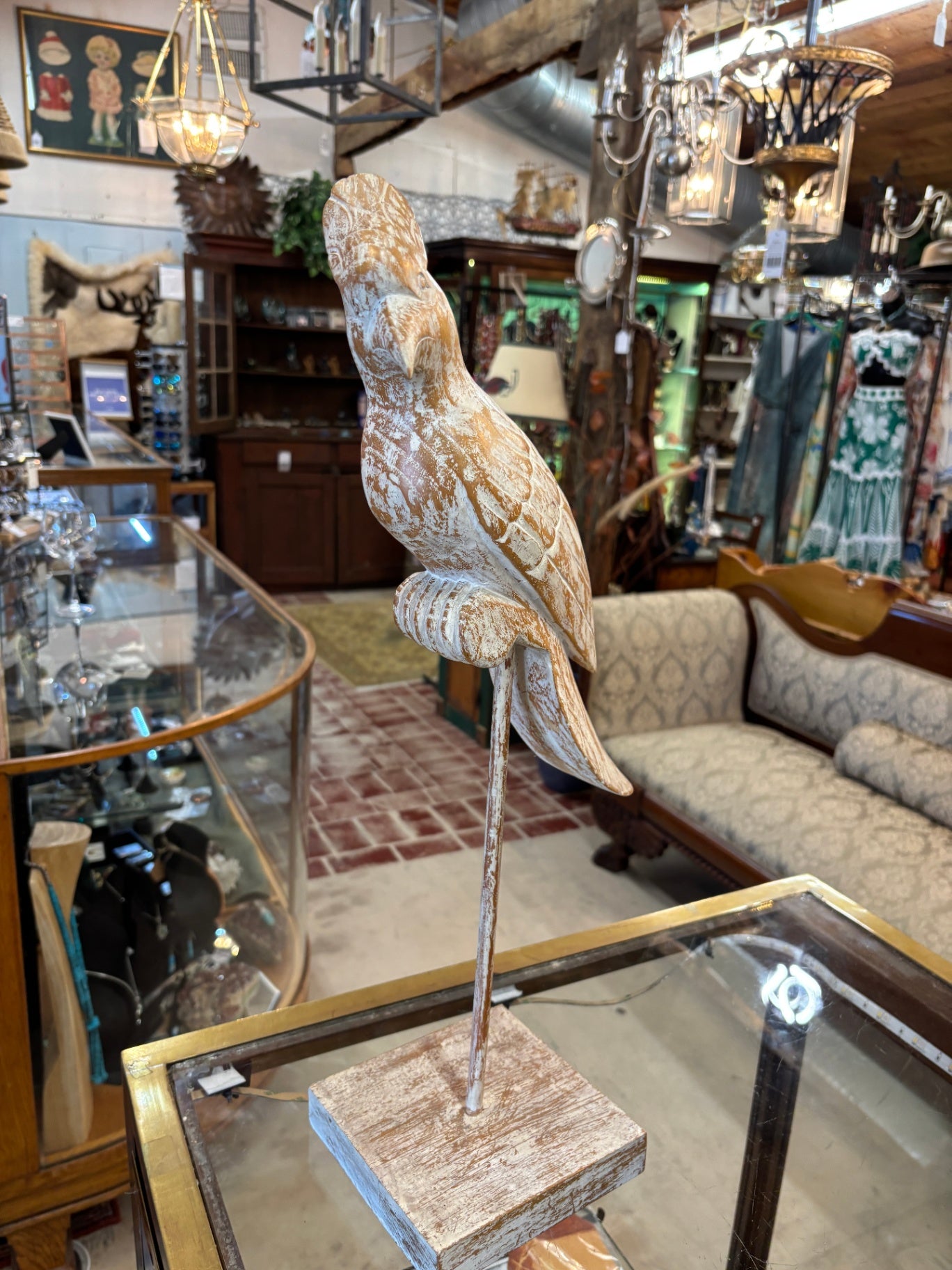 Vintage hand-carved wooden parrot statue perched on a stand