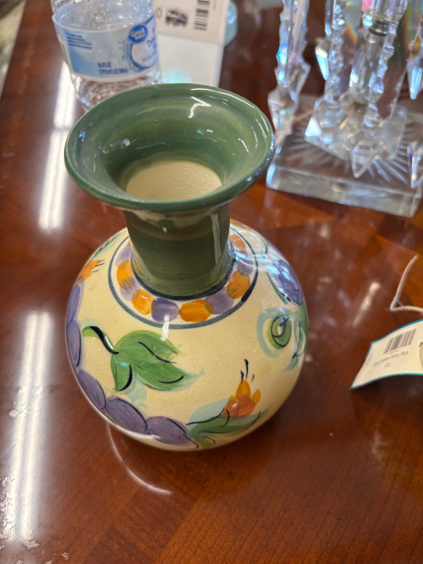 hand-painted clay or ceramic pottery vase featuring a green neck and a colorful floral pattern.