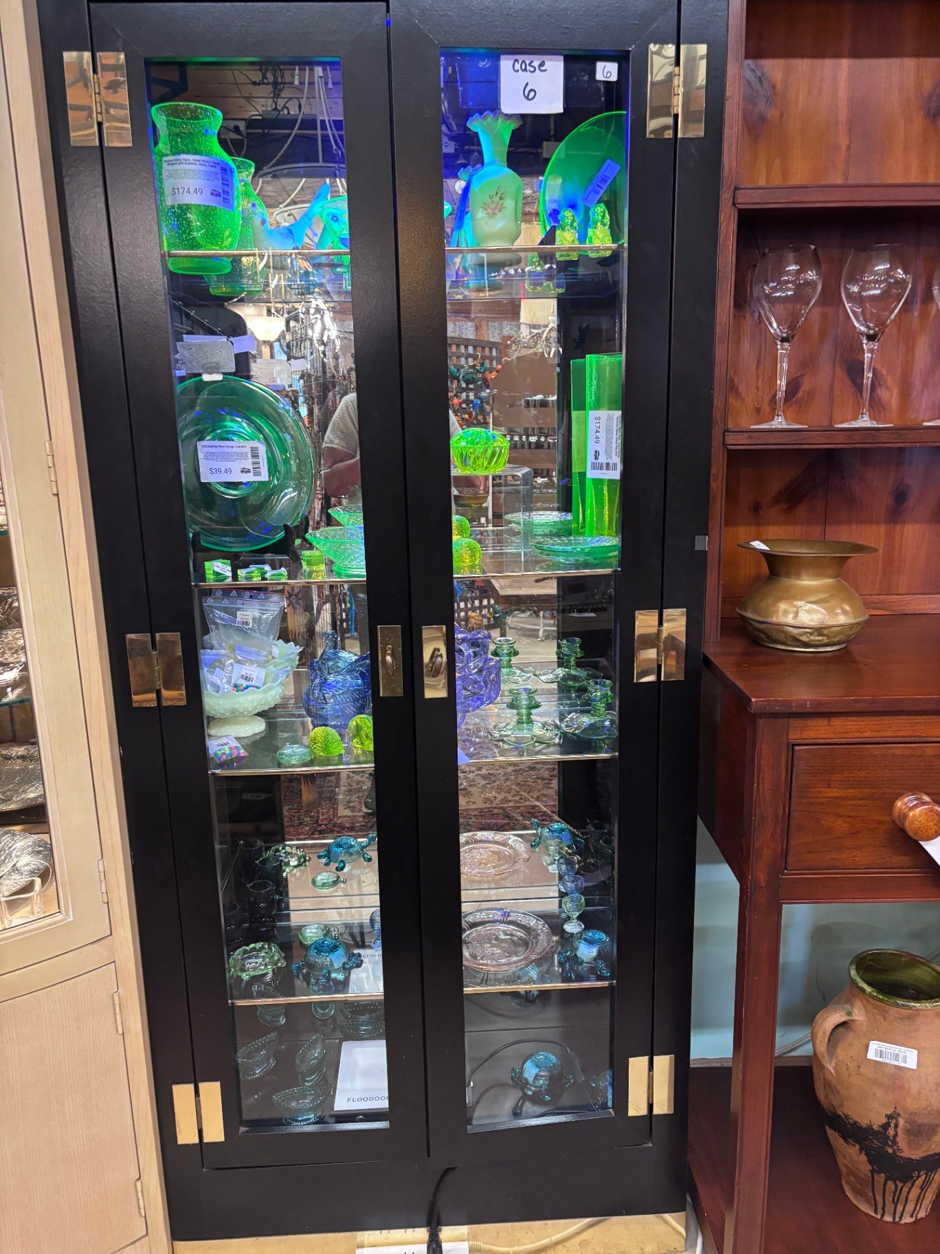 Black display case with mirrored back and gold trim on glass shelves