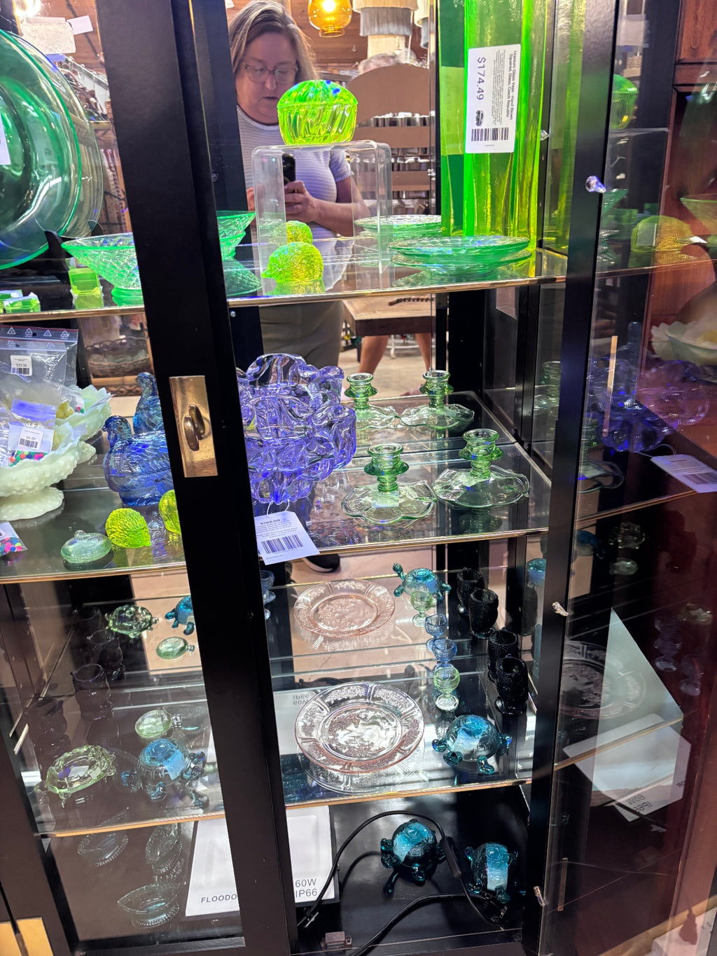 Black display case with mirrored back and gold trim on glass shelves