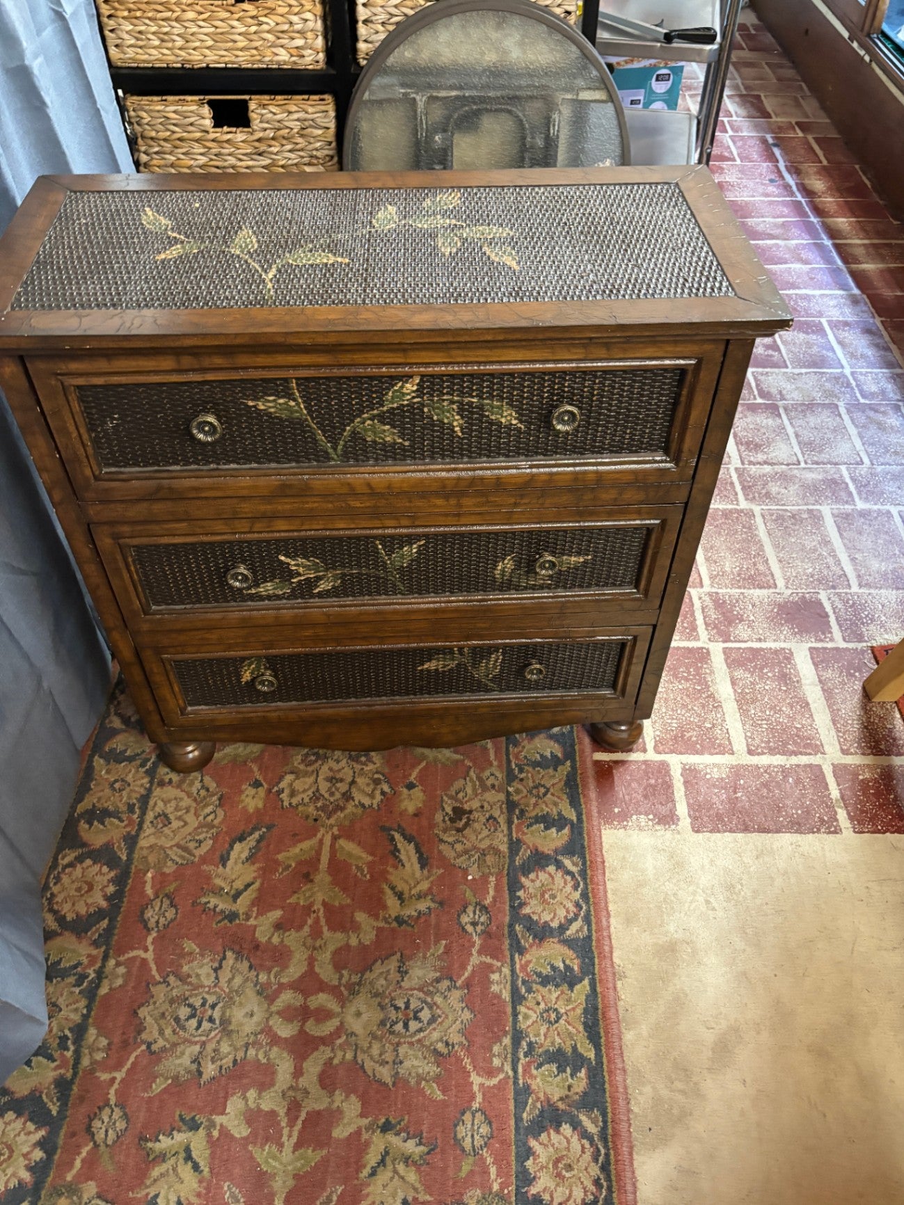 Coast to Coast Imports three-drawer accent chest featuring woven textured panel inserts with hand-painted botanical leaf vine accents