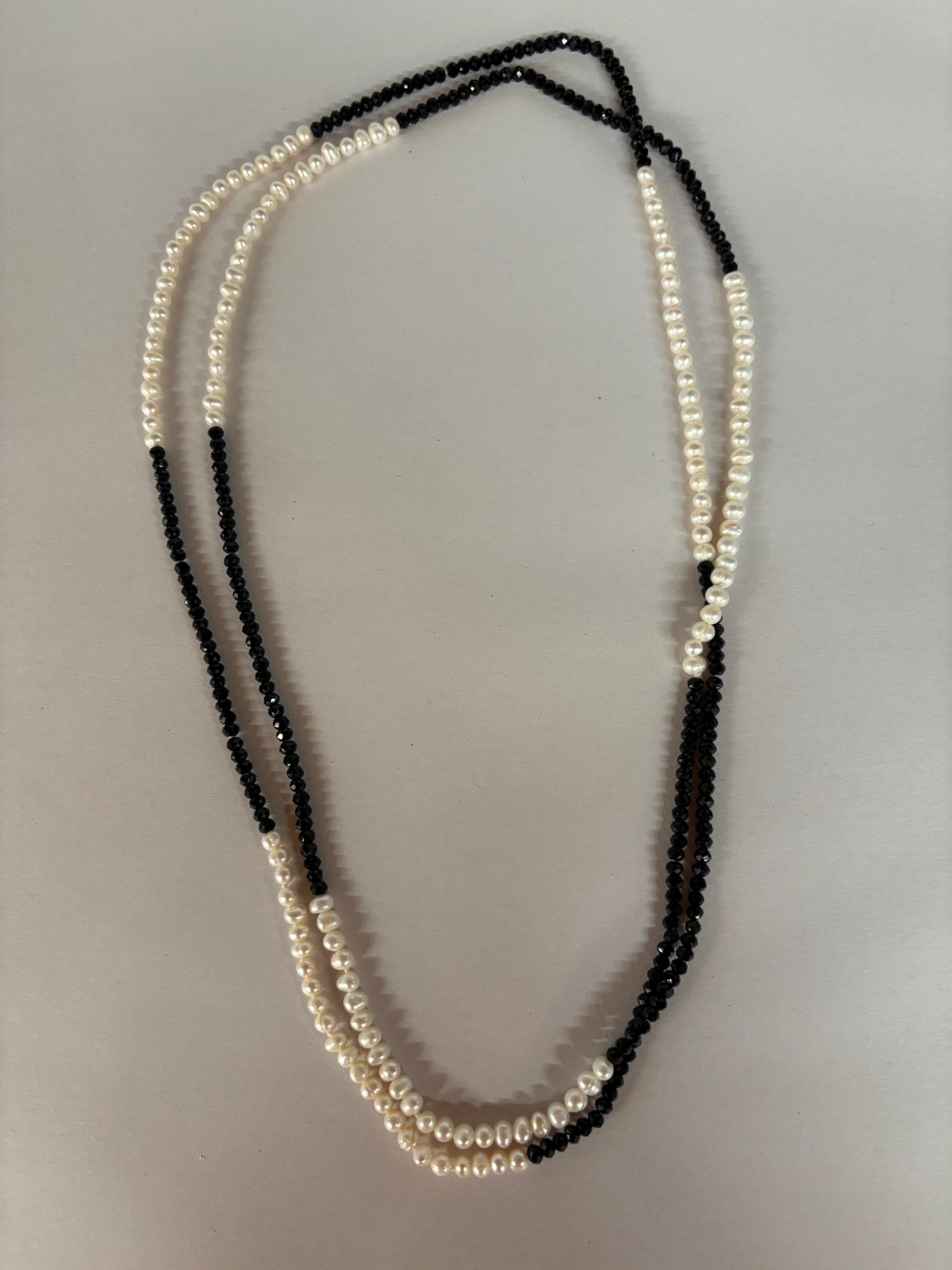  long torsade necklace features a striking combination of lustrous white freshwater pearls and alternating sections of sparkling black faceted crystal beads