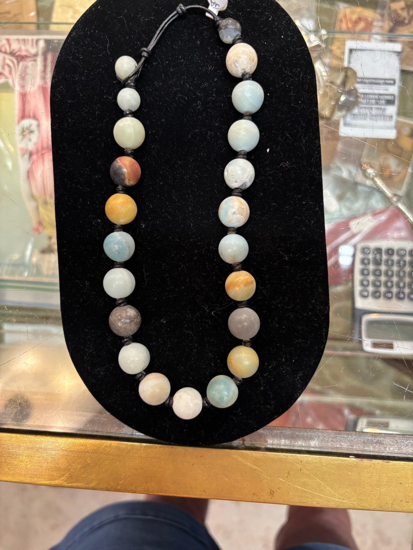 Multi-color gemstone beaded necklace features smooth, earthy-toned round stones strung on an adjustable black cord