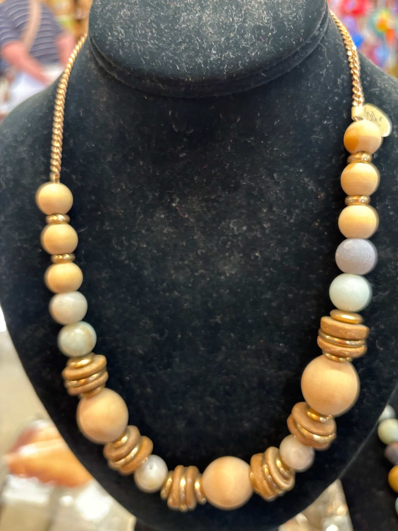 Chunky statement necklace features an earthy mix of graduated natural wood, stone, and textured gold-tone spacer beads
