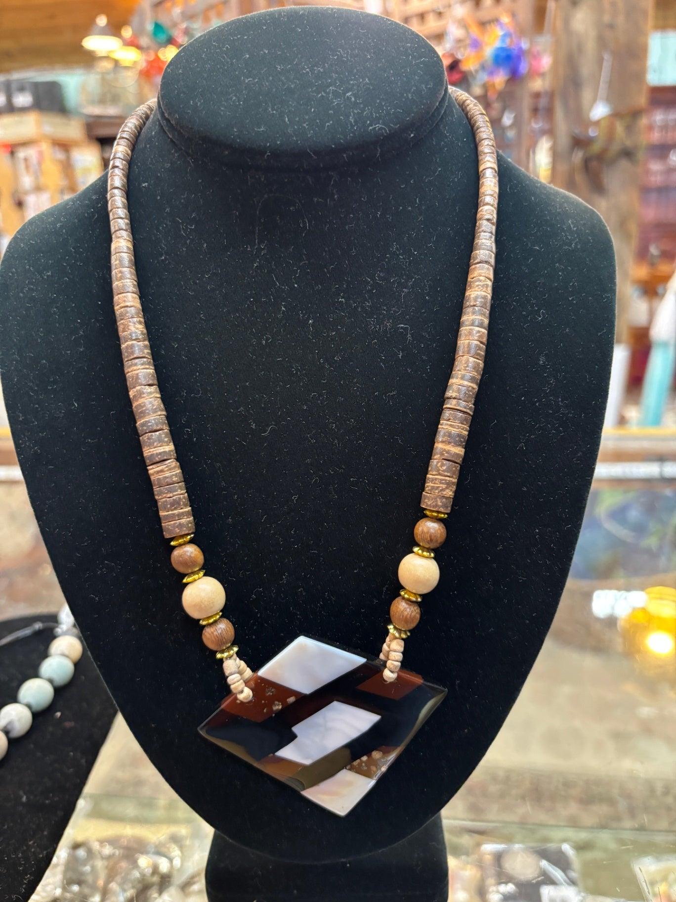 Bohemian tribal statement necklace features textured wooden disc beads and a striking geometric multi-tone pendan