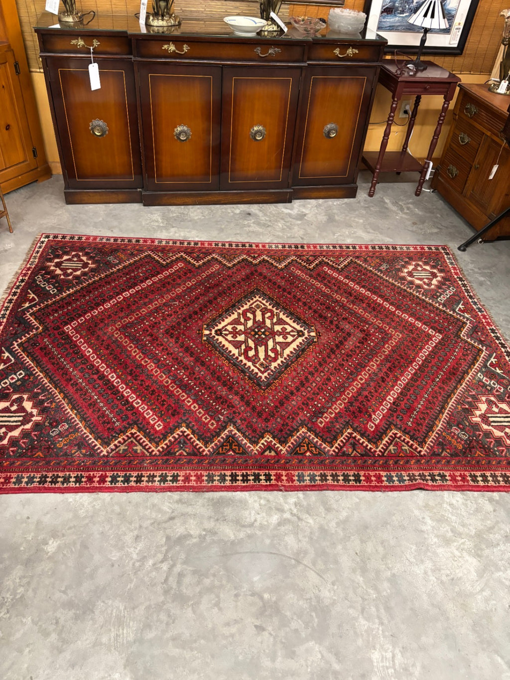  Hand-knotted tribal rug with a bold geometric center medallion set against a rich red and rust field
