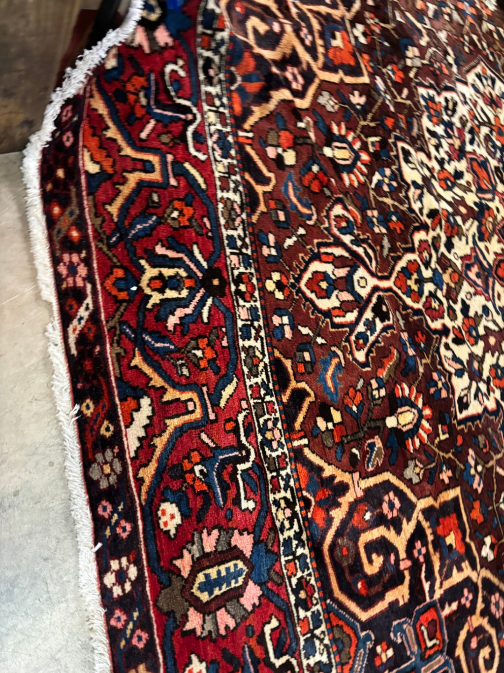  Hand-knotted tribal rug with a bold geometric center medallion set against a rich red and rust field