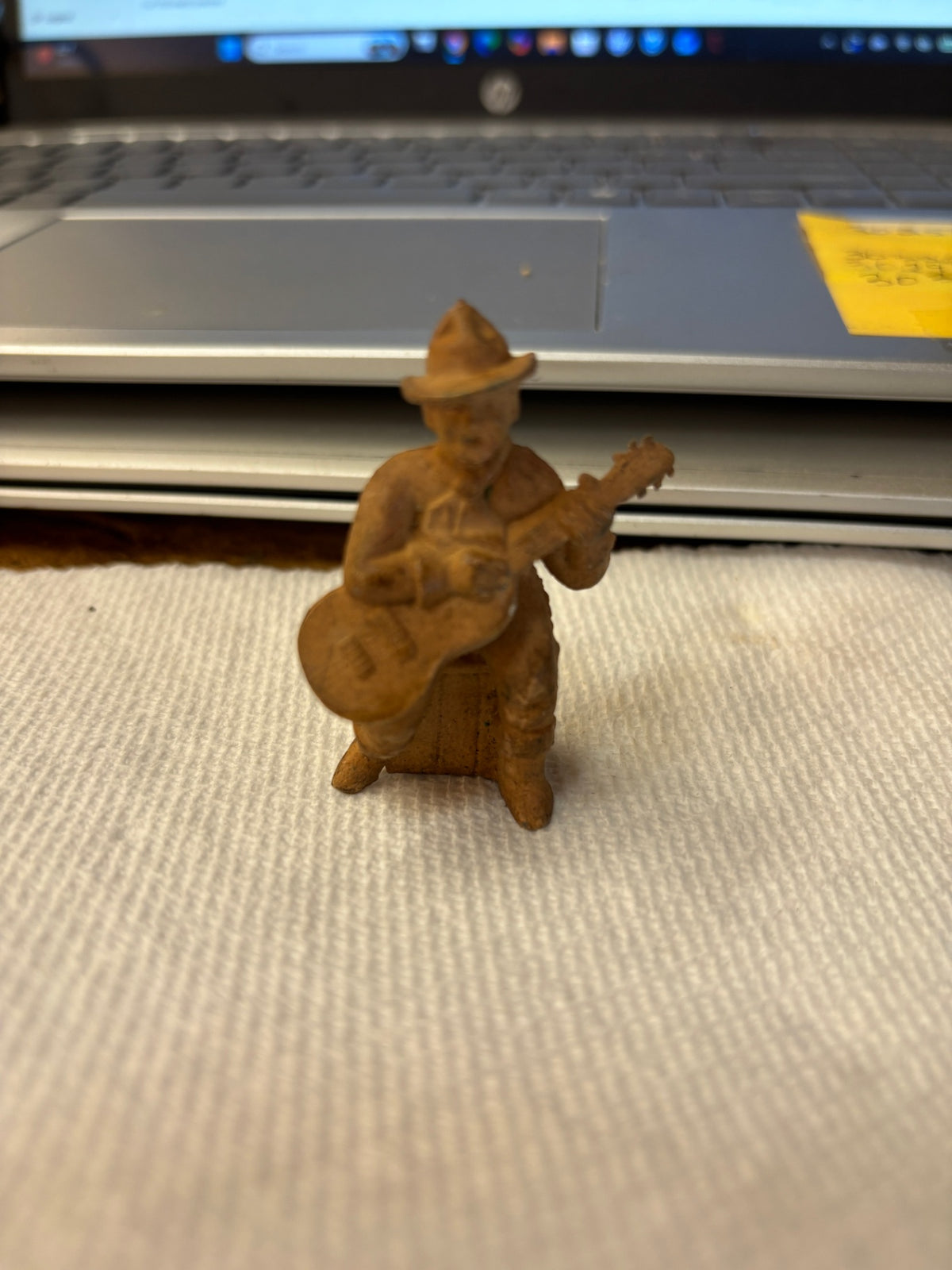 "chubby cowboy" playing a guitar, made of brown vinyl or rubber-like plastic commonly found in Western playsets