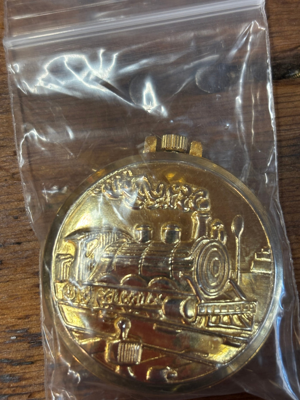 Comemorative gold-tone pocket watch featuring an embossed steam locomotive on the cover