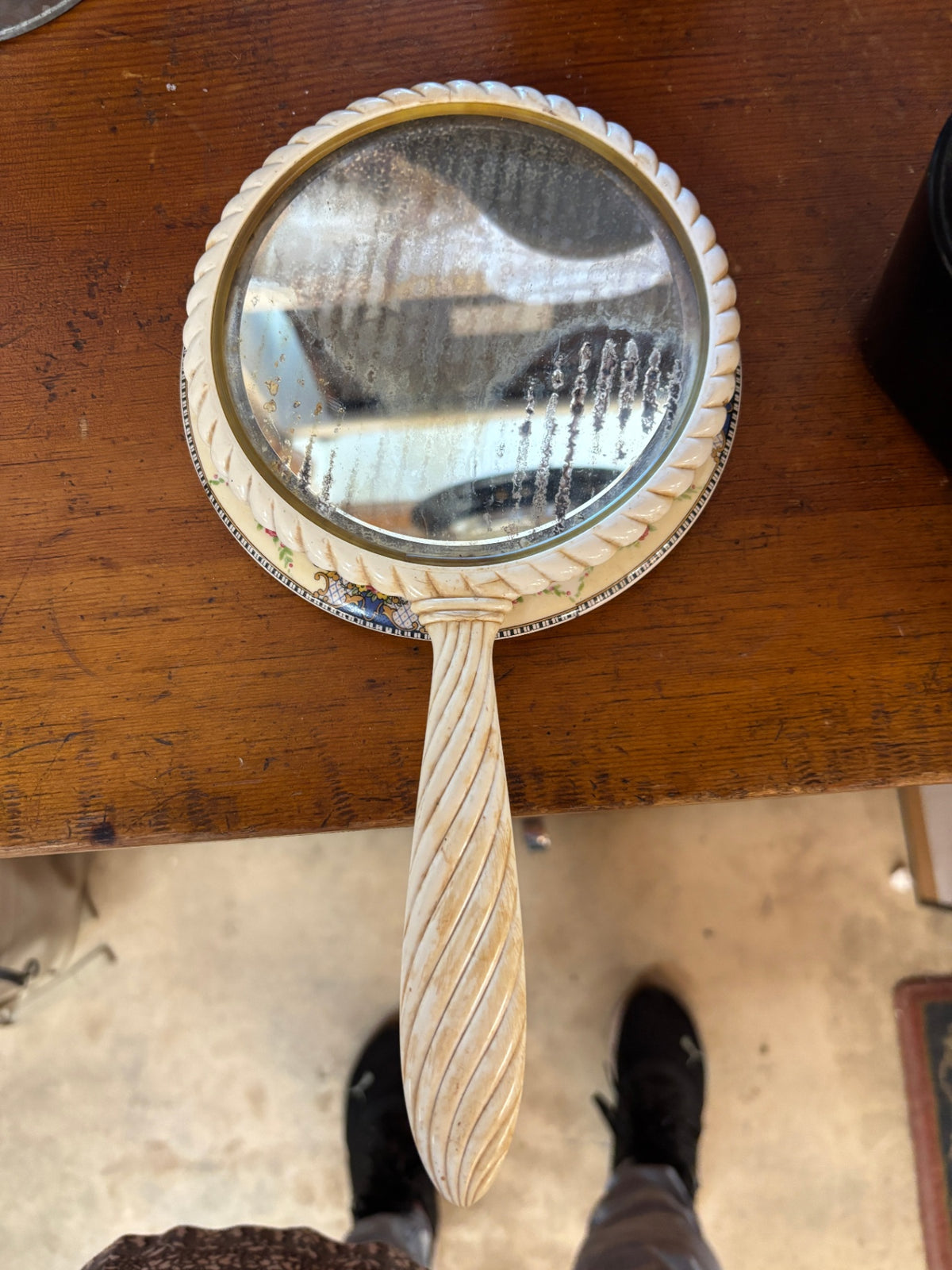 Vintage cream-colored hand mirror with a distinctive twisted handle and a matching floral ceramic decorative plate