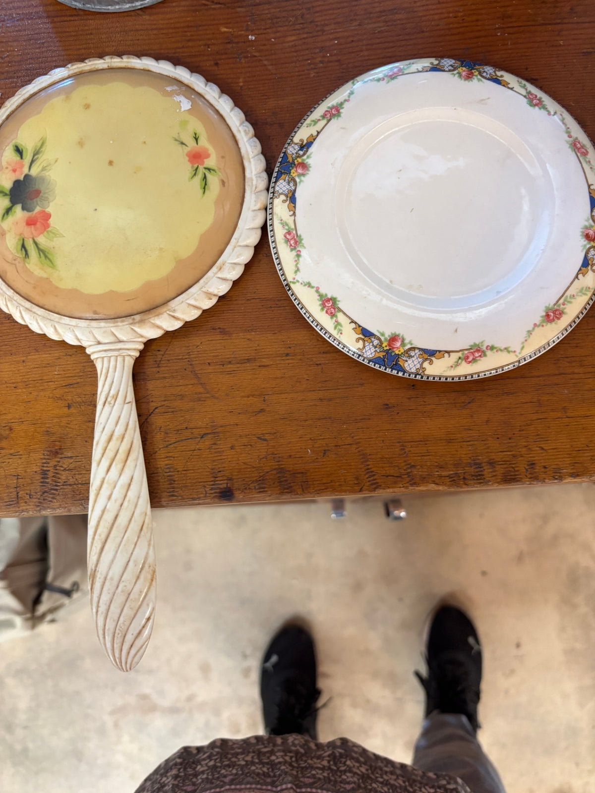 Vintage cream-colored hand mirror with a distinctive twisted handle and a matching floral ceramic decorative plate