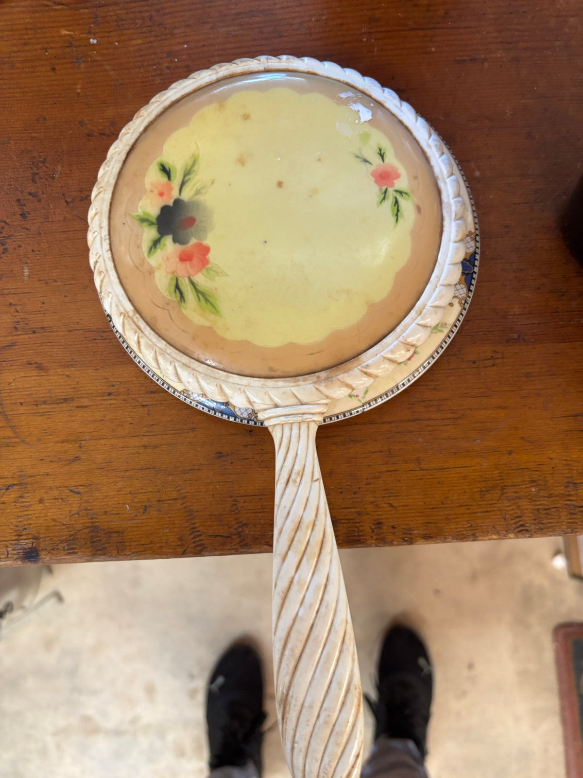 Vintage cream-colored hand mirror with a distinctive twisted handle and a matching floral ceramic decorative plate