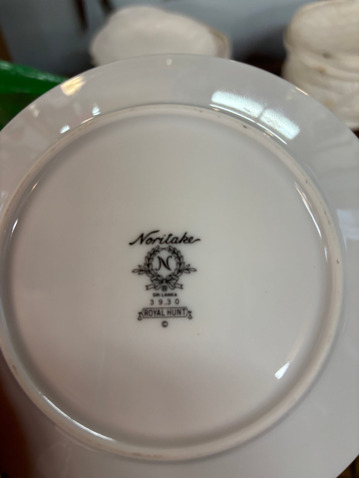 White ceramic saucer with a dark green border and gold trim from the Noritake Royal Hunt