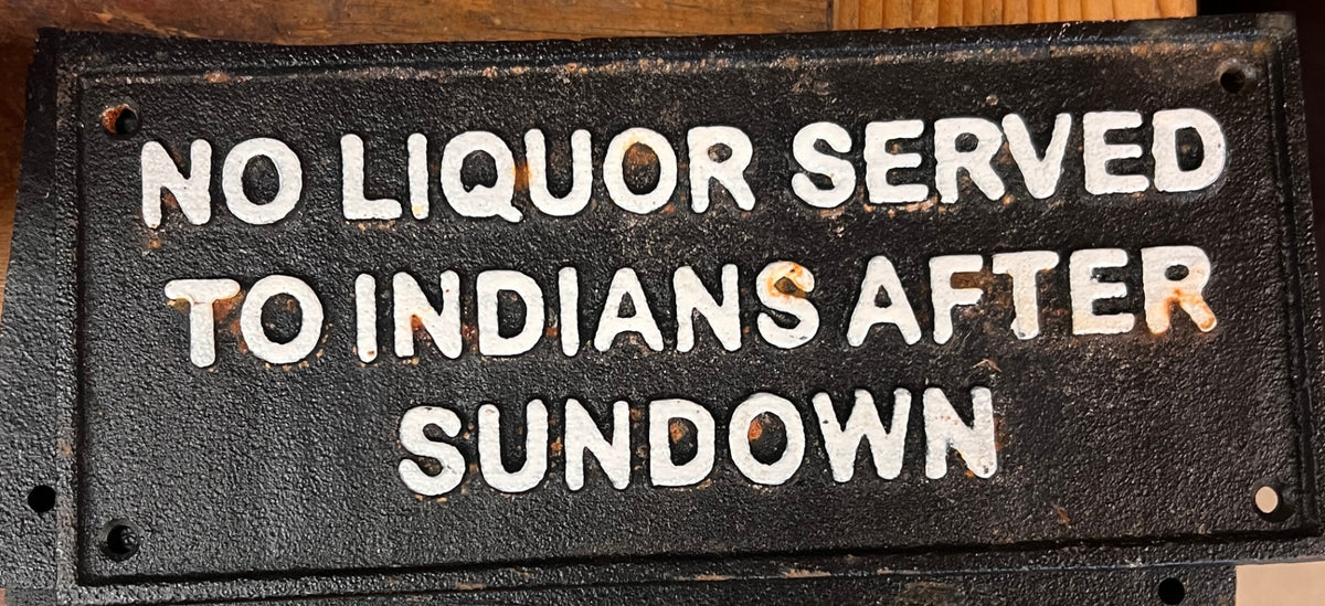 Black Cast Iron NO LIQUOR SERVED TO INDIANS AFTER SUNDOWN" with raised white lettering.