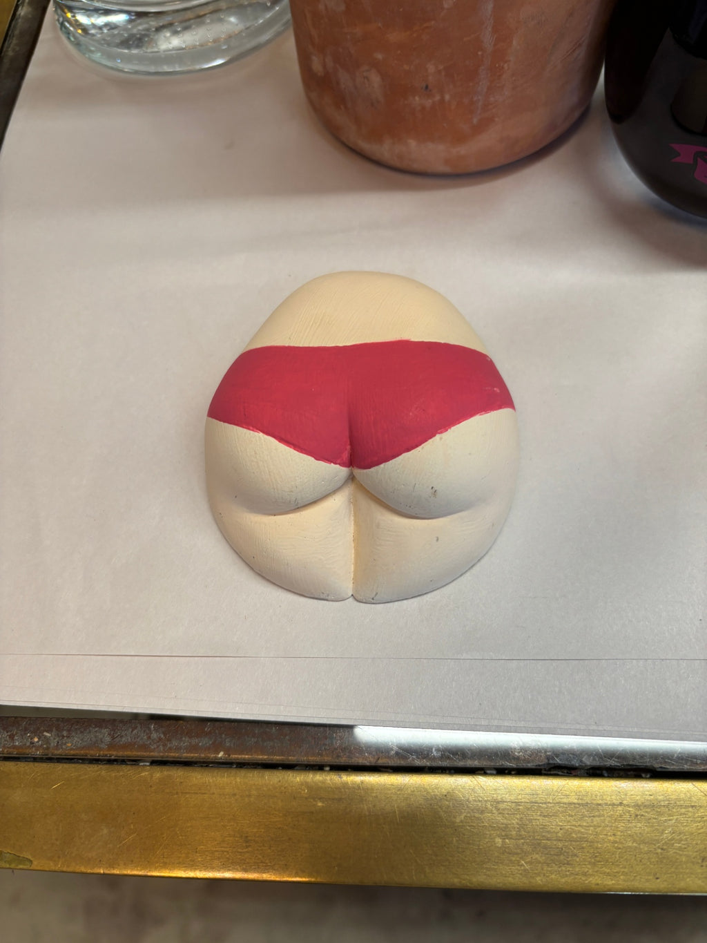 Ceramic novelty sculpture depicting a stylized human bottom wearing bright pink underwear
