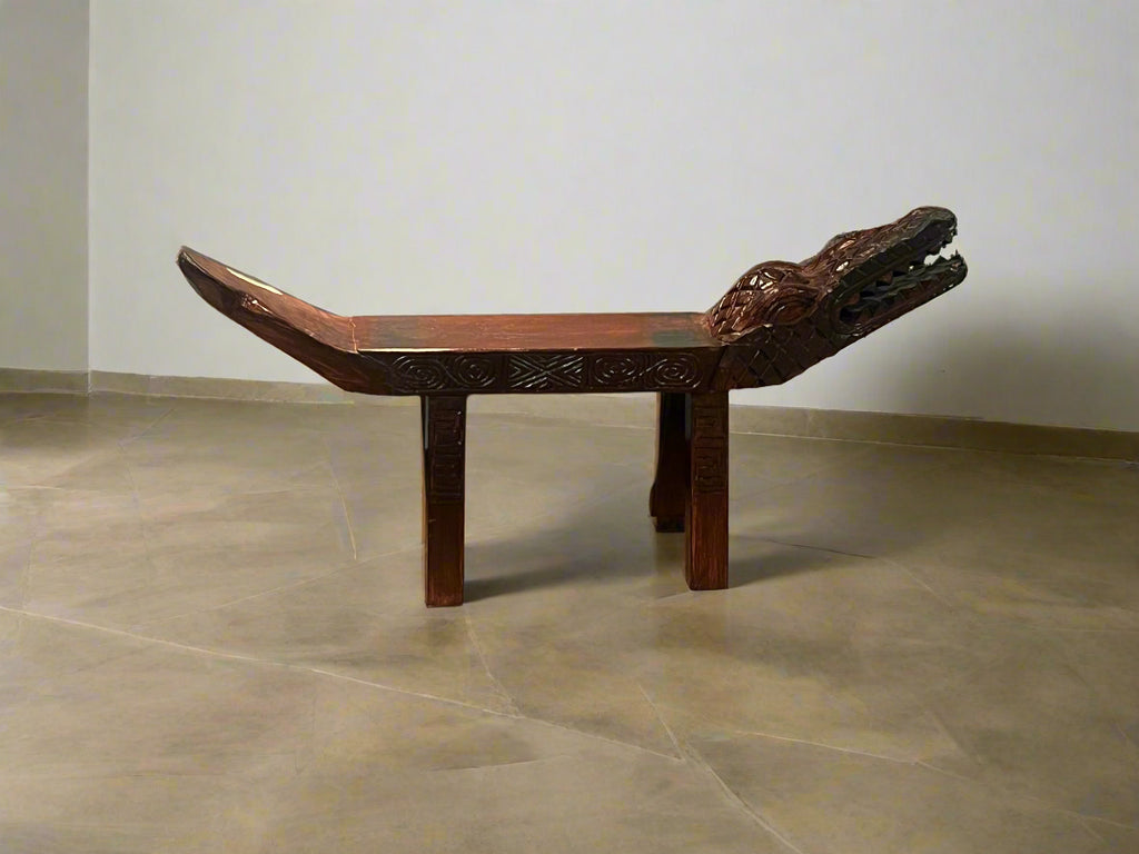 Wooden bench with intricate carvings in front of a store display.