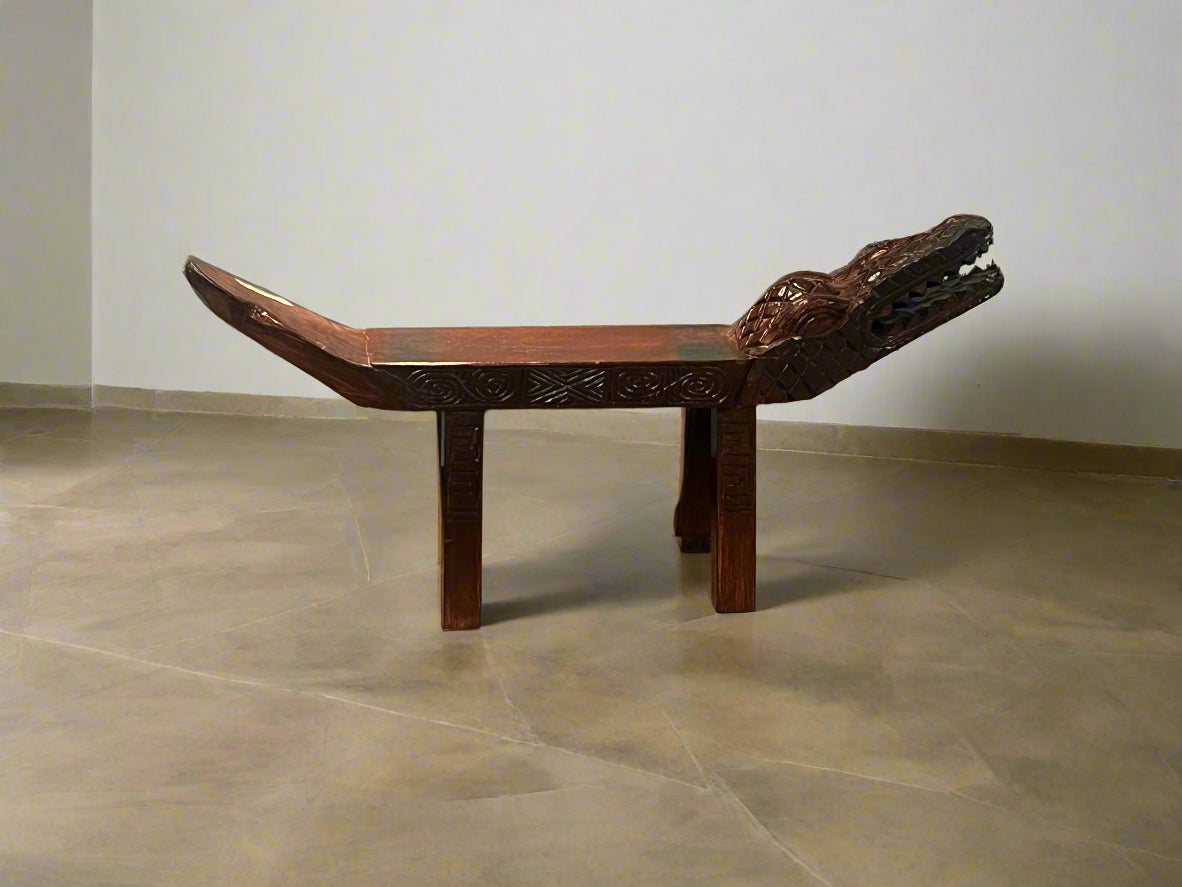 Wooden bench with intricate carvings in front of a store display.