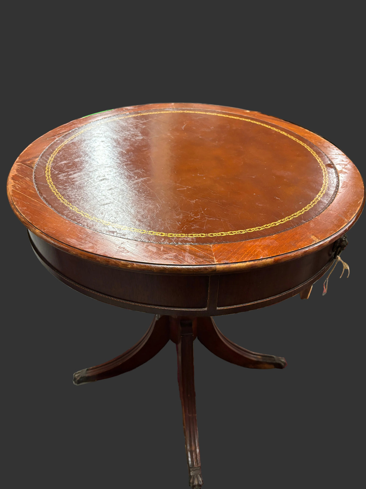 A round wooden pedestal table with a glossy brown finish and gold decorative inlay on the tabletop