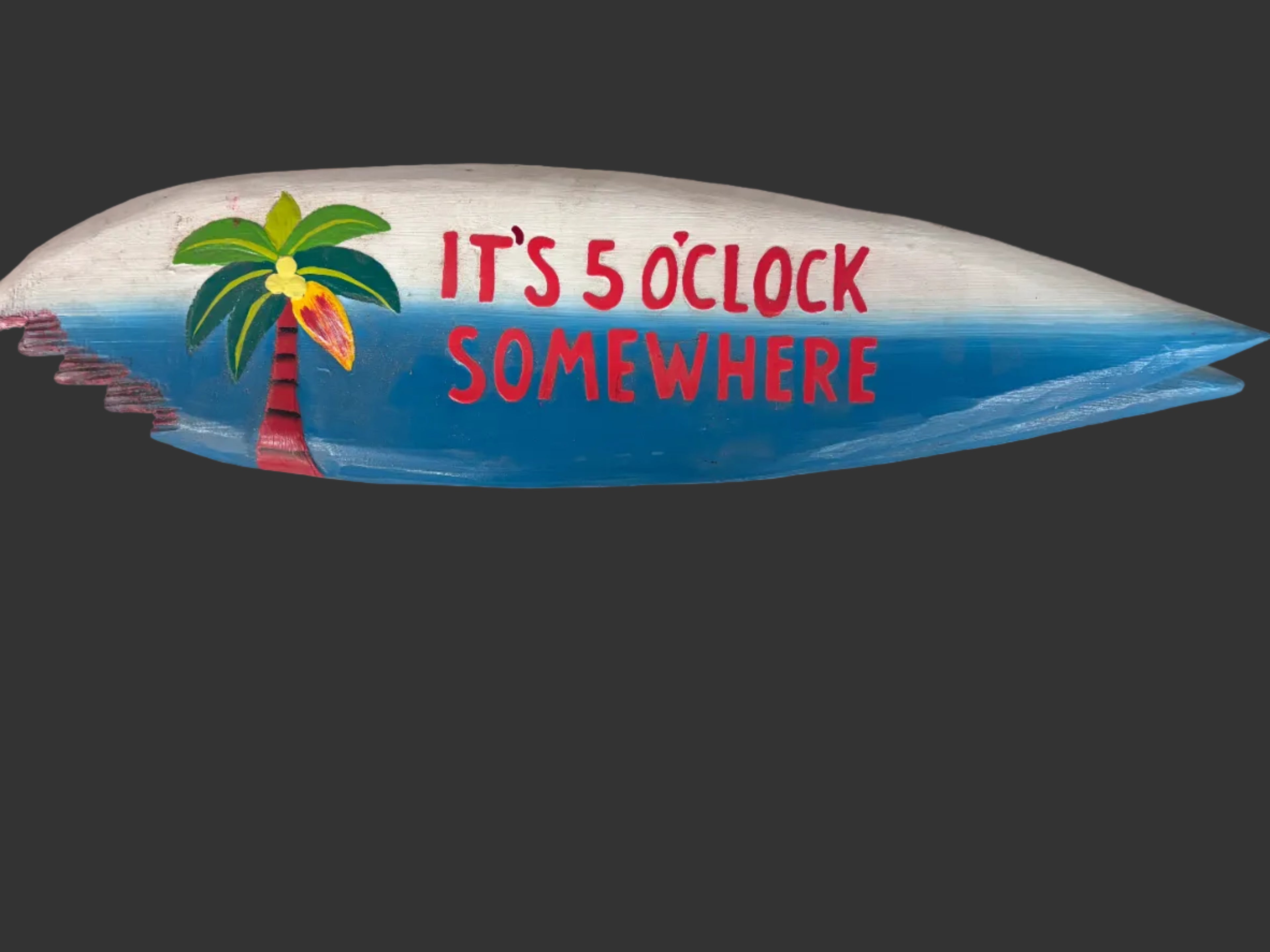 A carved wooden shark-shaped sign with a blue and white painted finish, featuring the text 'IT'S 5 O'LOCK SOMEWHERE' in red and a green tropical flower illustration.