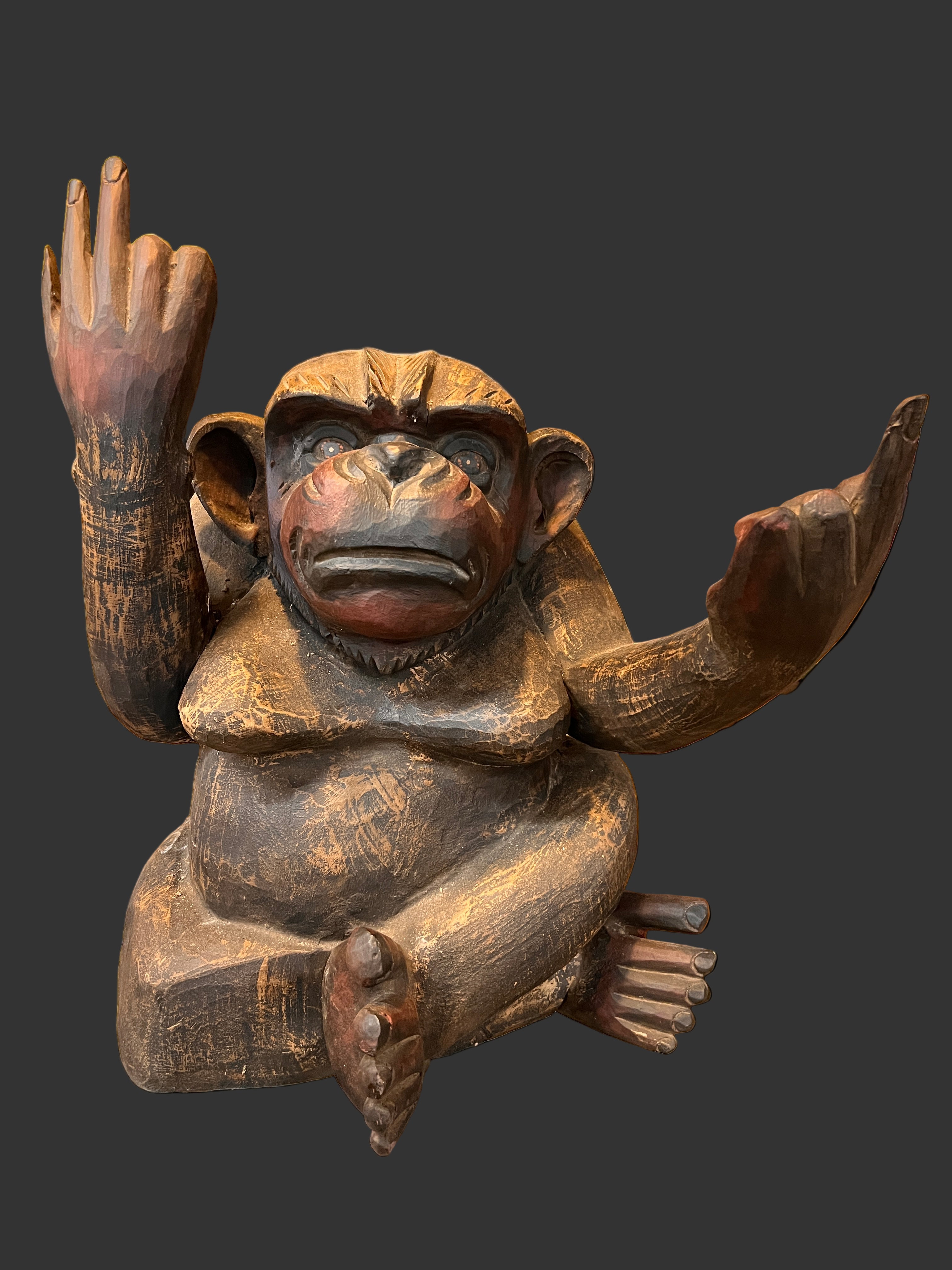 Wooden statue of Monkey figure in a store setting with framed pictures on the wall.